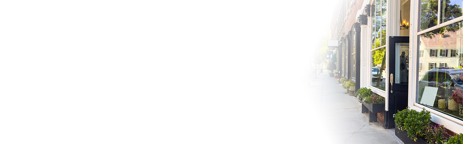 row of main street shopping district stores fading into white gradient background