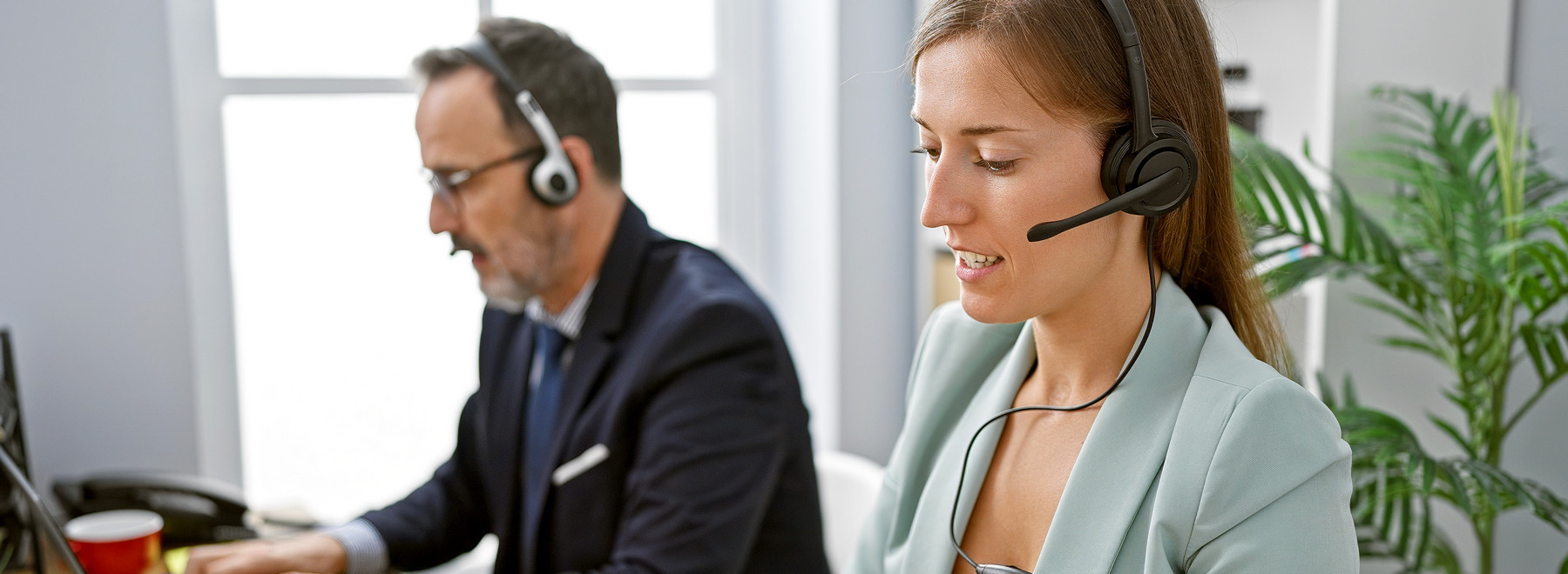 male and female call center reps with headphones sitting in front of monitors assisting customers online