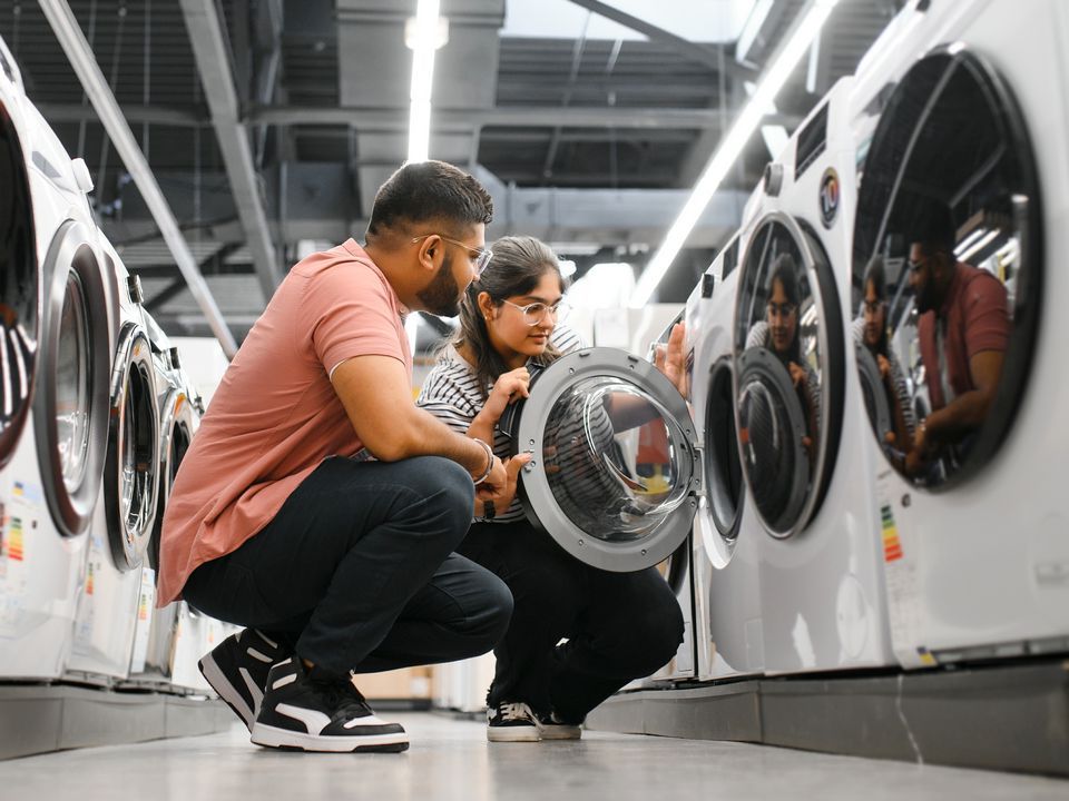 male female couple shopping for washing machines in electronics appliance store