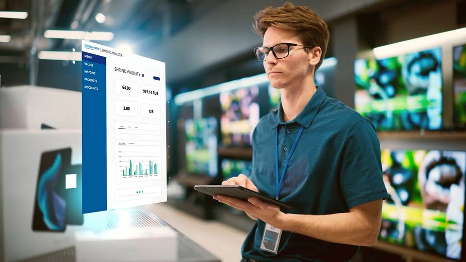 male retail store clerk in electronics department reviews shrink analyzer data on tablet device