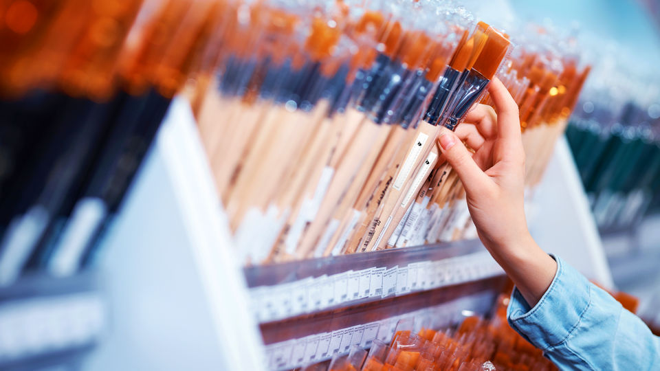 customer hand reaching for paintbrush with eas label in retail stationery art supply store