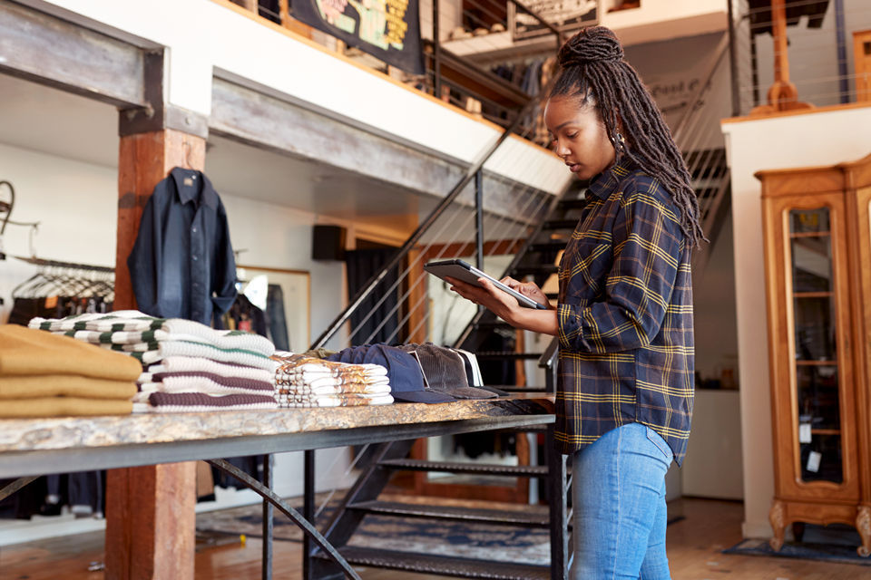 retail manager reviews store compliance data on a device in an upscale retail clothing and accessories store