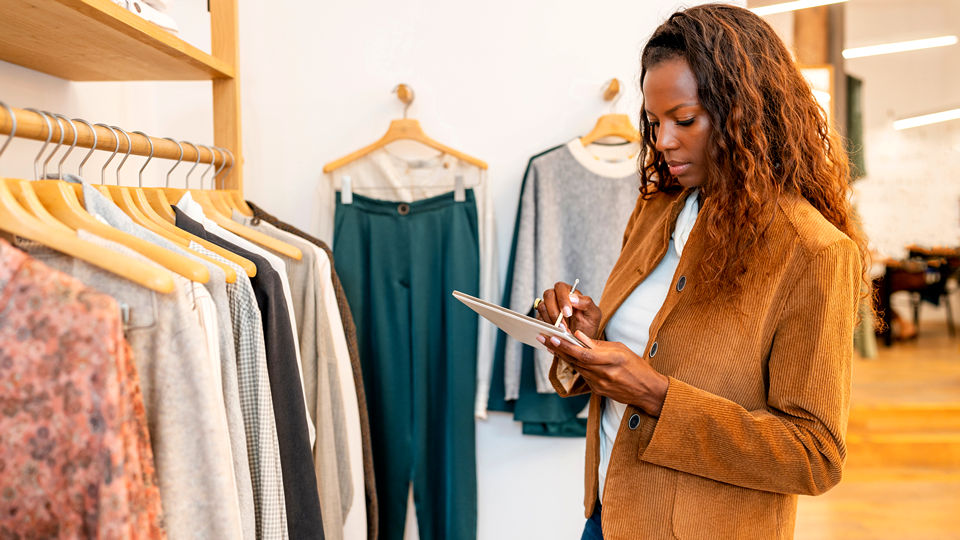 female retail store associate manager reviewing inventory on her electronic tablet device