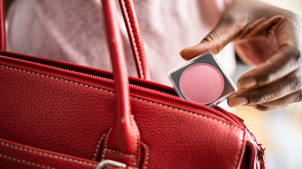 shoplifter putting cosmetics in her purse without paying at retail store