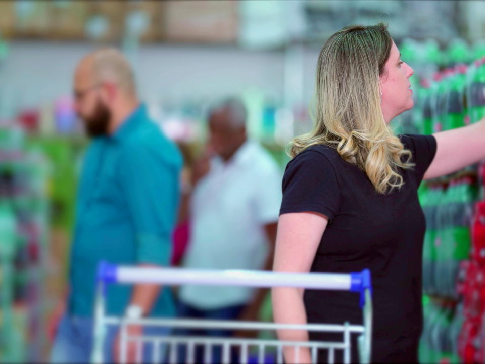 multi-ethnic clientele pushing shopping carts and slecting items from shelves in warehouse retail store