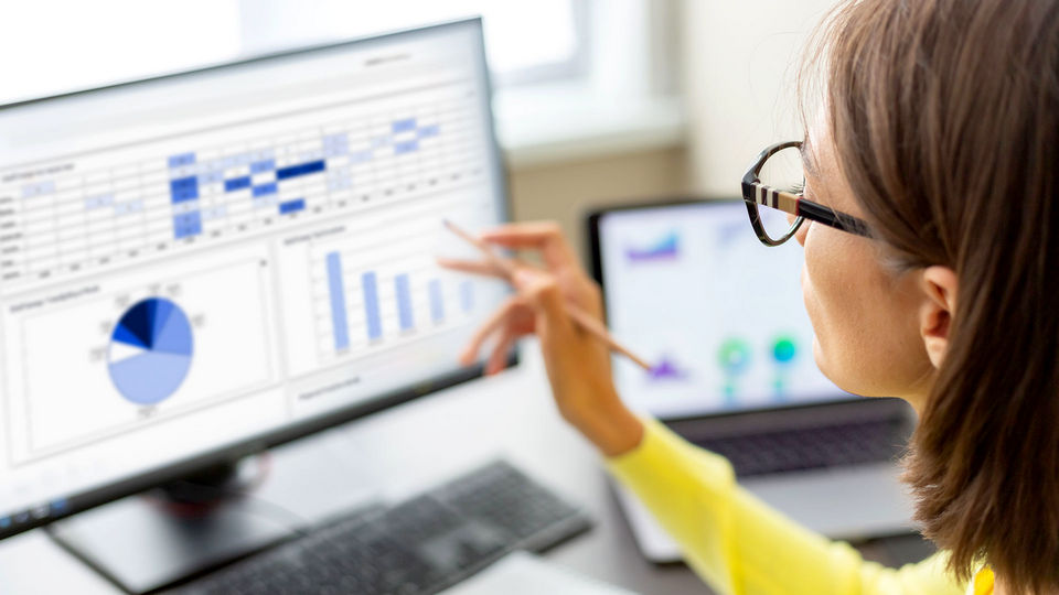 woman reviewing secure retail data screens on multiple monitors